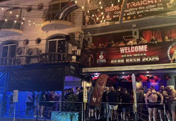 Studs Bear Bar, a gay place in Puerto Vallarta, during Bear Bash 2025. Men gather outside the bar, some wearing harnesses. Night scene, lively.