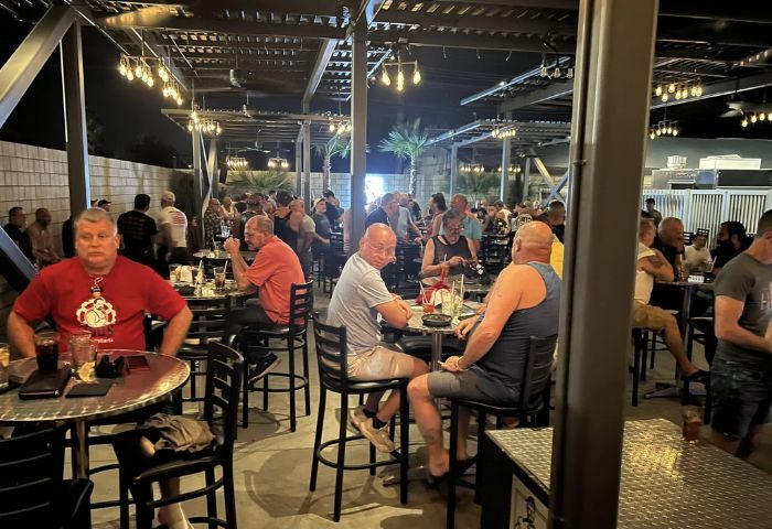 Studs Bear Bar, a gay place in Puerto Vallarta, at night. Men gather at tables under string lights in an open-air bar setting. Gay travel.