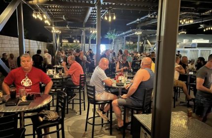 Studs Bear Bar, a gay place in Puerto Vallarta, at night. Men gather at tables under string lights in an open-air bar setting. Gay travel.