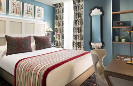 Les Tournelles, stylish gay hotel in Paris' Marais. Bedroom with queen bed, desk, mirror, & blue walls. Gay travel lodging.
