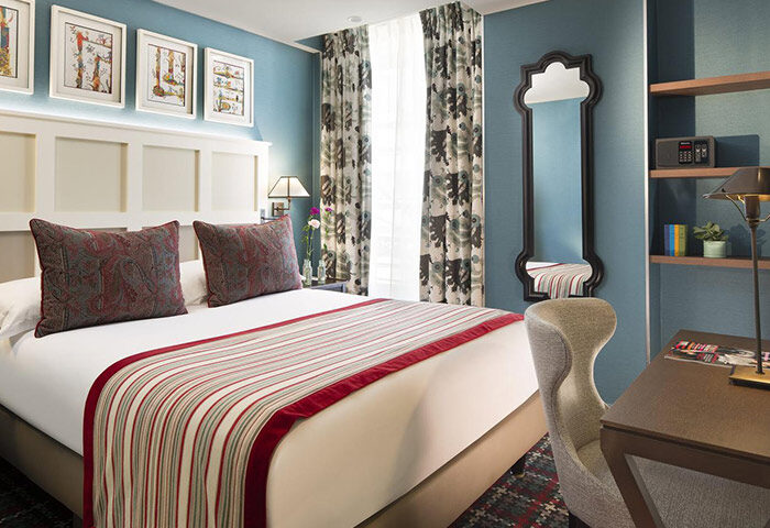 Les Tournelles, stylish gay hotel in Paris' Marais. Bedroom with queen bed, desk, mirror, & blue walls. Gay travel lodging.