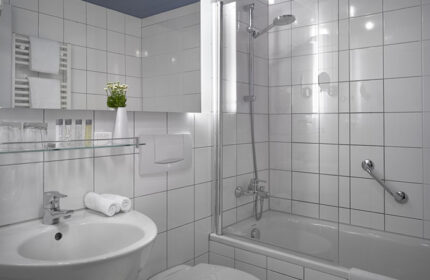 Stylish bathroom at K+K Hotel Fenix, Prague Old Town. White tile, sink, tub/shower. Gay-friendly hotel for comfortable travel.