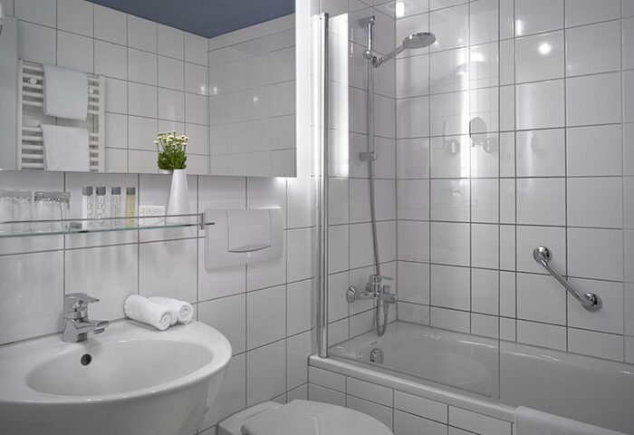 Stylish bathroom at K+K Hotel Fenix, Prague Old Town. White tile, sink, tub/shower. Gay-friendly hotel for comfortable travel.