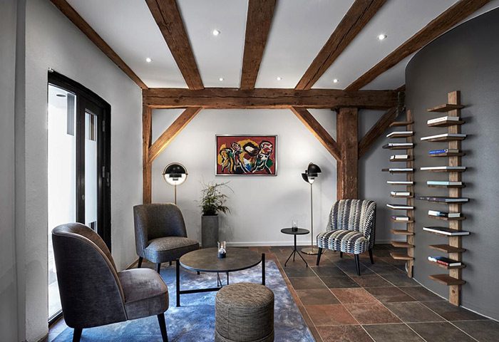 Stylish luxury at 71 Nyhavn Hotel, Copenhagen. Gay-friendly hotel lounge area with exposed beams, modern furniture, and a unique bookshelf.