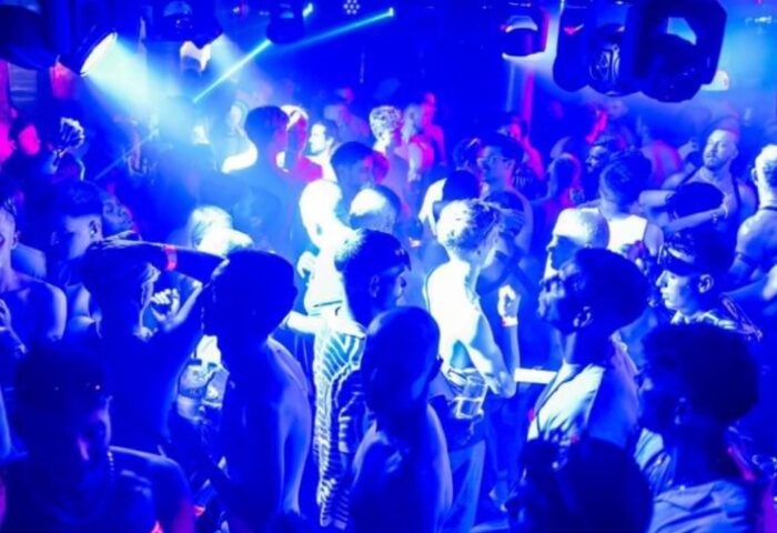 Sub 101 Manchester: Gay men dancing in a crowded club. Blue lighting, shirtless men, nightlife scene. Gay travel advice.