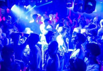 Sub 101 Manchester: Gay men dancing in a crowded club. Blue lighting, shirtless men, nightlife scene. Gay travel advice.