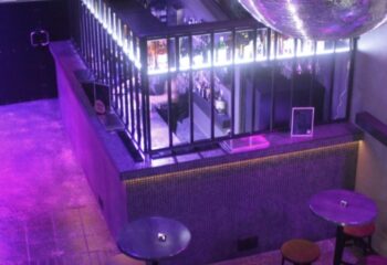 Melbourne's Subway Sauna bar area with disco ball, purple lighting, and cocktail tables. Gay sauna travel advice.