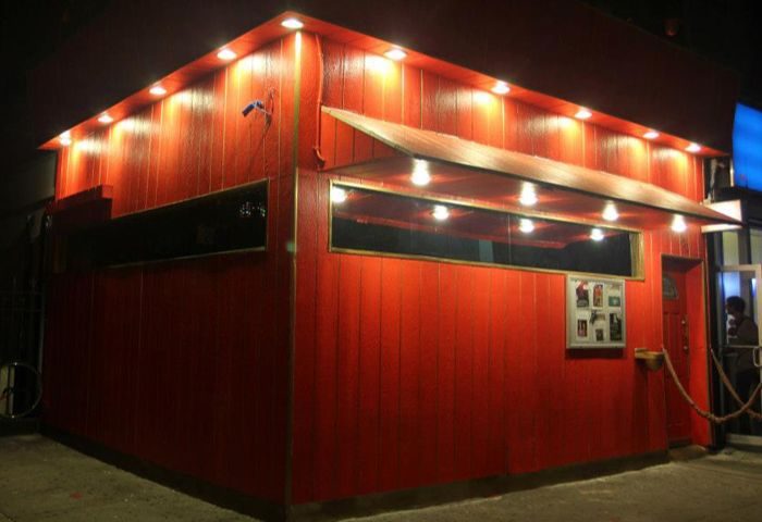 Suite NYC: Exterior view of the Suite gay bar in New York. Red wood paneling, awning, and bright lights. A popular gay pub in NYC.