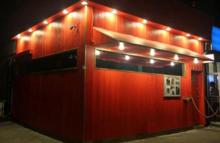 Suite NYC: Exterior view of the Suite gay bar in New York. Red wood paneling, awning, and bright lights. A popular gay pub in NYC.
