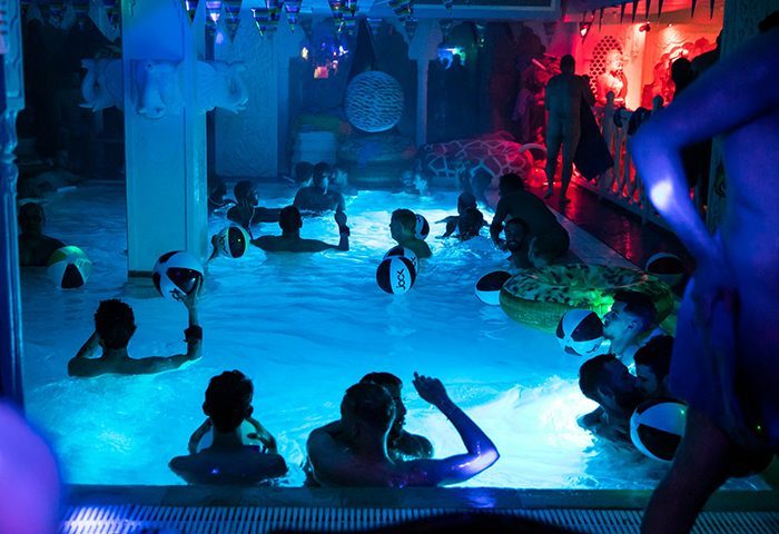 Sun City Paris: Gay men enjoy a pool party with beach balls and colorful lights. A fun travel destination for gay men in Paris.