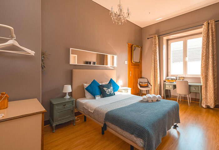 Sunset Destination Hostel Lisbon double room with private bathroom. Gay travel lodging with desk, chair, and butterfly pillow.