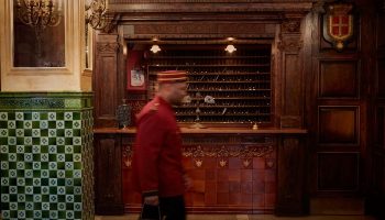 The Jane Hotel's lobby in NYC, a super-cool hotel for gay travelers. A bellhop walks past the reception desk. The hotel has a vintage aesthetic.
