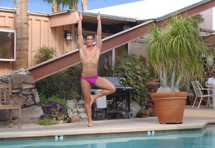 Gay men's travel: Man doing yoga at Triangle Inn Palm Springs, a super gay men-only hotel, by the pool. Vacation and relaxation.