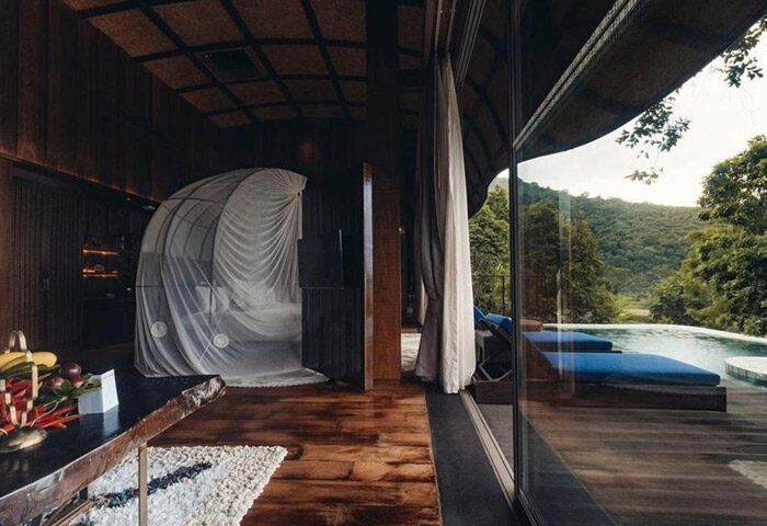 Keemala gay hotel Phuket honeymoon suite. Luxury villa interior with draped bed, pool view, and tropical landscape. Best gay-friendly resort.