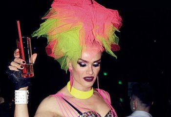 Drag queen at SuperFabric Club, Istanbul. Pink and green headpiece, holding a drink. Gay nightlife in Turkey. LGBTQ+ travel.