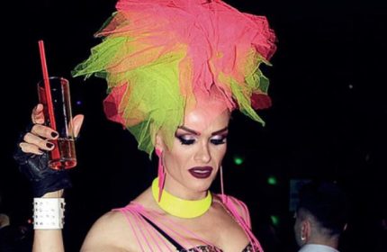 Drag queen at SuperFabric Club, Istanbul. Pink and green headpiece, holding a drink. Gay nightlife in Turkey. LGBTQ+ travel.