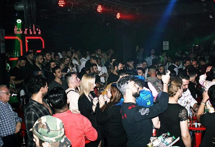 Crowd at SuperFabric Club Istanbul. Gay nightlife scene with men and women dancing under red lights in a dark, packed club. Gay travel advice.