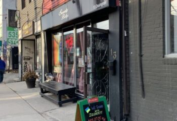 Sweaty Betty's Bar in Toronto. Ossington gay bar with a sign supporting Ukraine. Popular gay travel destination for men.