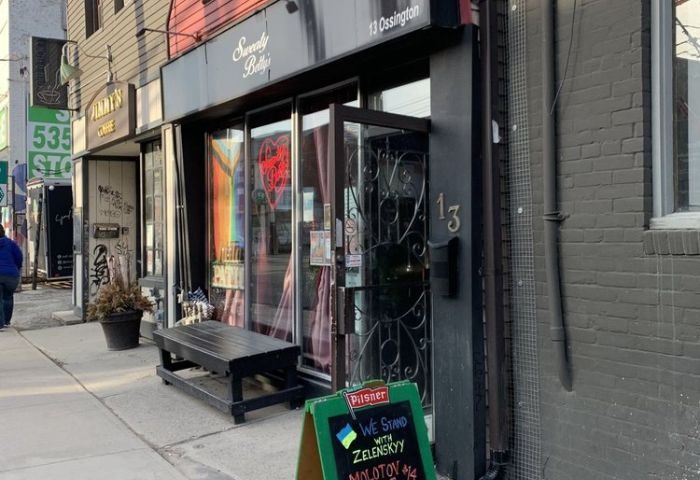 Sweaty Betty's Bar in Toronto. Ossington gay bar with a sign supporting Ukraine. Popular gay travel destination for men.