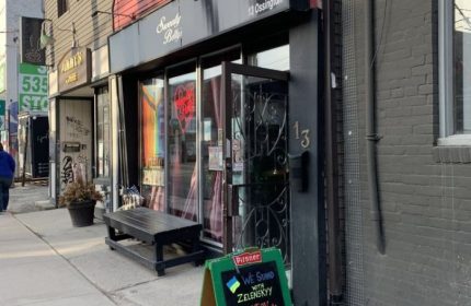 Sweaty Betty's Bar in Toronto. Ossington gay bar with a sign supporting Ukraine. Popular gay travel destination for men.