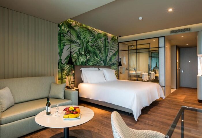 TUI Blue Gardens adults-only suite at Savoy Signature, Madeira. Gay-friendly hotel room with bed, sofa, wine, and tropical decor.