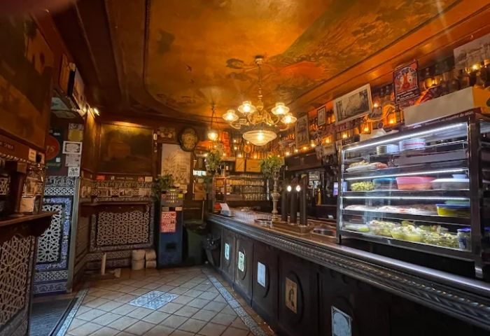 Interior of Taberna de Ángel Sierra, a gay bar in Madrid. Ornate decor, warm lighting, and a classic Spanish tavern atmosphere.