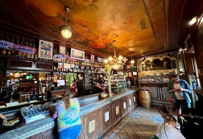 Interior view of Taberna de Ángel Sierra, a historic gay bar in Madrid. The bar features a vintage design, ornate ceiling, and a bustling atmosphere.