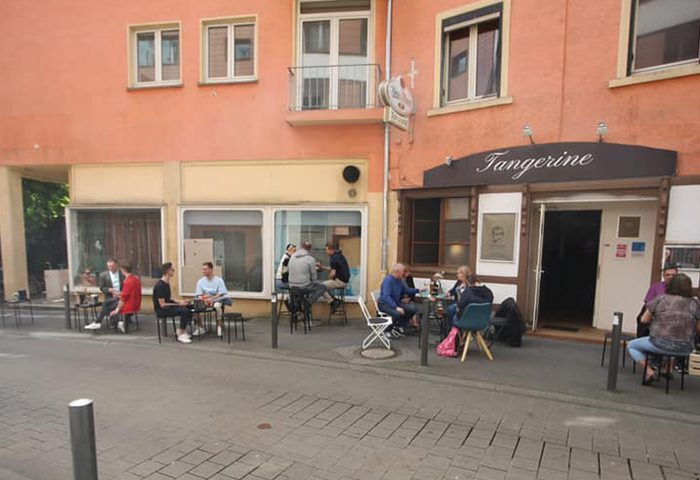 Tangerine bar in Frankfurt, a gay travel destination. People sit outside, enjoying drinks. Gay bar scene, Frankfurt nightlife.