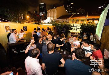 Crowded outdoor area at Tantric Bar, Singapore's popular gay bar. Men socializing, drinking. Nightlife scene. Gay travel.