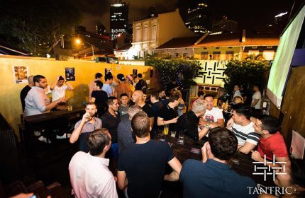 Crowded outdoor area at Tantric Bar, Singapore's popular gay bar. Men socializing, drinking. Nightlife scene. Gay travel.
