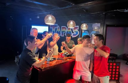 Gay men toasting at Tapas Waikiki, a gay-friendly drink place in Honolulu. Bar scene with drinks, friends, and a fun atmosphere.