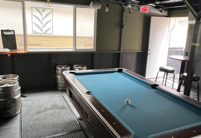 Interior of Waikiki gay bar in Honolulu with a pool table, kegs, tables, and stools. A gay-friendly drink place for travelers.