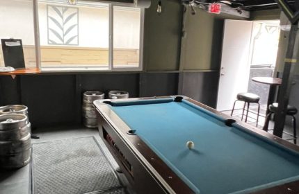 Interior of Waikiki gay bar in Honolulu with a pool table, kegs, tables, and stools. A gay-friendly drink place for travelers.