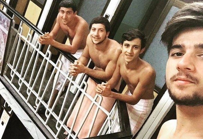Gay travel: Four shirtless men in towels at Tarihi Galatasaray Hamami, Istanbul. Turkish bath experience, gay-friendly travel destination.