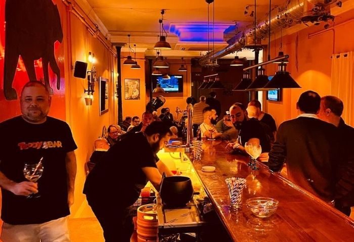 Interior of Teddy Bar, a gay bar in Barcelona. Men are gathered at the bar, enjoying drinks in a warm, inviting atmosphere.