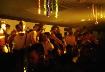 Tek Yon Club Istanbul: Gay men gather in a dimly lit space with decorations. Nightlife scene for gay travel in Istanbul, Turkey.