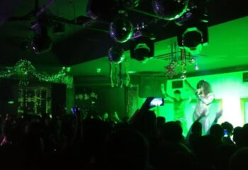 Tek Yon Club Istanbul: Gay club scene with performers on stage under green lights, crowd visible. Nightlife for gay men travelers.