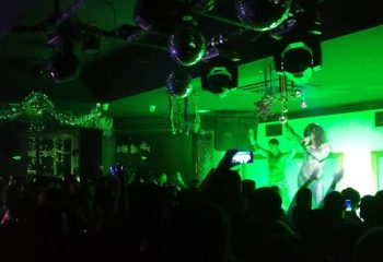 Tek Yon Club Istanbul: Gay club scene with performers on stage under green lights, crowd visible. Nightlife for gay men travelers.