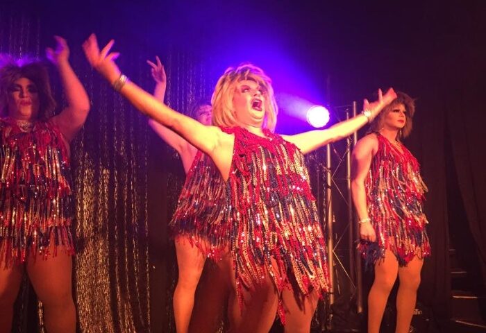 Drag queens perform at The 86 in Melbourne. Gay travel advice: The 86 bar is a popular gay venue with a drag show. Red fringe dresses.