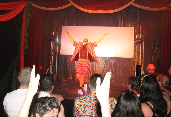 Melbourne, Australia: Drag queen on stage at The 86, a gay bar. Audience members with hands raised. Gay travel advice.