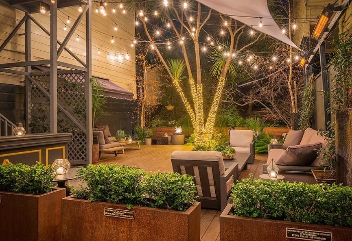 The Academy Social Club in San Francisco: Outdoor patio with lights, plants, and lounge seating. A gay-friendly travel destination.