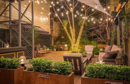 The Academy Social Club in San Francisco: Outdoor patio with lights, plants, and lounge seating. A gay-friendly travel destination.