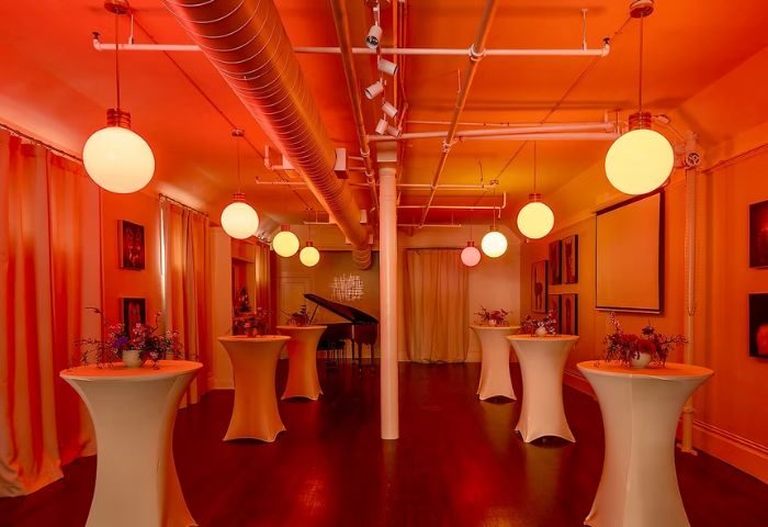 Interior of The Academy Social Club, San Francisco. Tables with flowers, piano, globe lights. Popular gay venue for socializing.