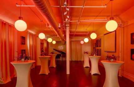Interior of The Academy Social Club, San Francisco. Tables with flowers, piano, globe lights. Popular gay venue for socializing.