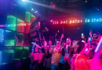 Drag queen performs at The Back Door gay bar in Cancun. Crowd holds up phones to record. Nightlife scene. LGBTQ+ travel.