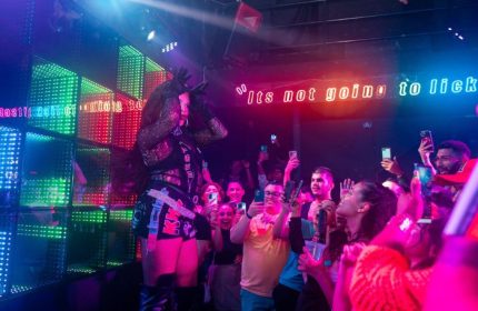 Drag queen performs at The Back Door gay bar in Cancun. Crowd holds up phones to record. Nightlife scene. LGBTQ+ travel.