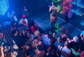 The Back Door Gay Bar in Cancun: Drag queen performing on stage to a packed crowd. Nightlife scene in a popular gay bar.