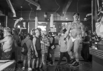 The Barracks dancefloor: Gay bar scene with a dancer in underwear on a platform. Men socializing in the background. Gay travel advice.