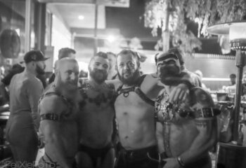The Barracks Experience: Group of gay men in leather harnesses and pup mask. Gay travel scene at The Barracks. Black and white.