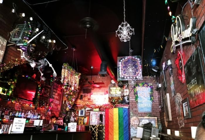 Interior of The Bayou Bar, a gay bar. Rainbow flag, decorations, skeleton, and lights adorn the space. Gay travel advice.